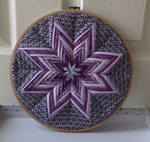 <p>Photograph of a pretty round cushion with purple and blue patterns</p>